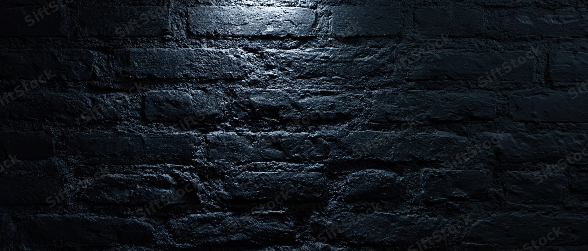 Dark textured brick wall illuminated by spotlight in dim interior space