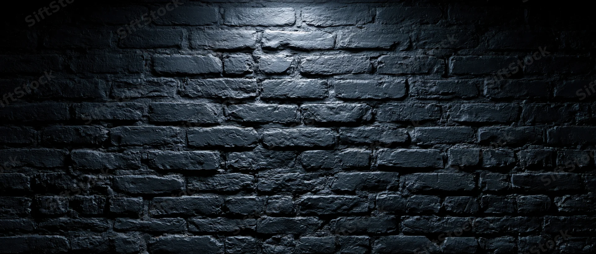 Black brick wall illuminated by spotlight with shadows and texture, creating a dark grunge background with copyspace