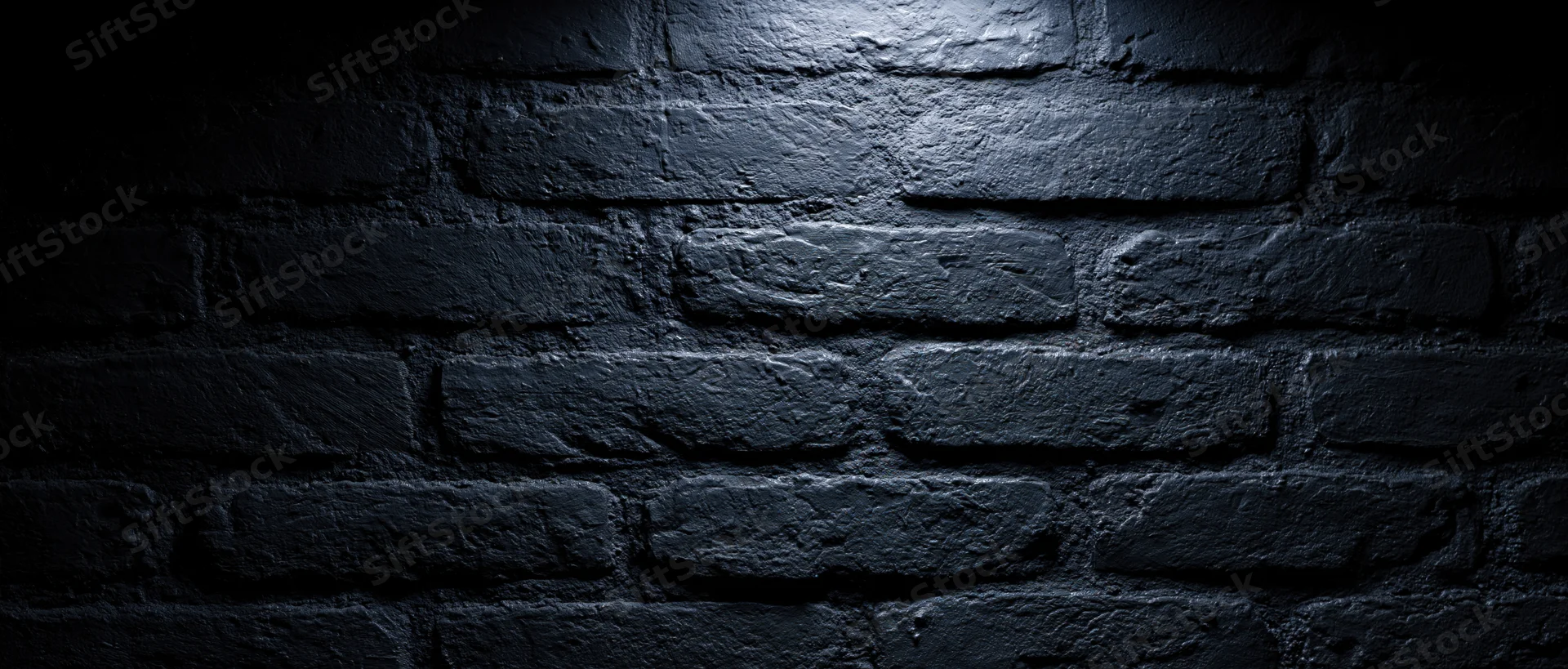Dark textured brick wall illuminated by spotlight in dim interior space