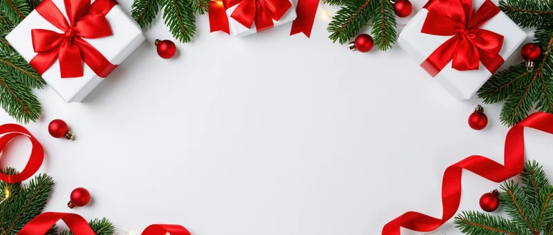 Christmas gifts with red ribbons and pine branches arranged in a frame on white background with copyspace
