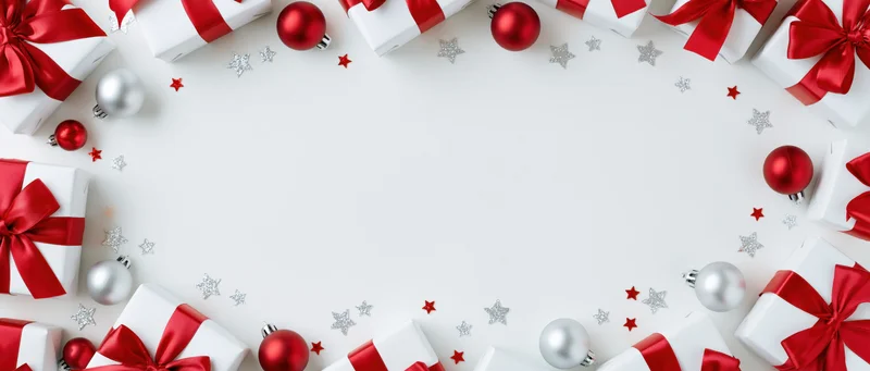 Christmas gifts and ornaments arranged in a border around a white copyspace background