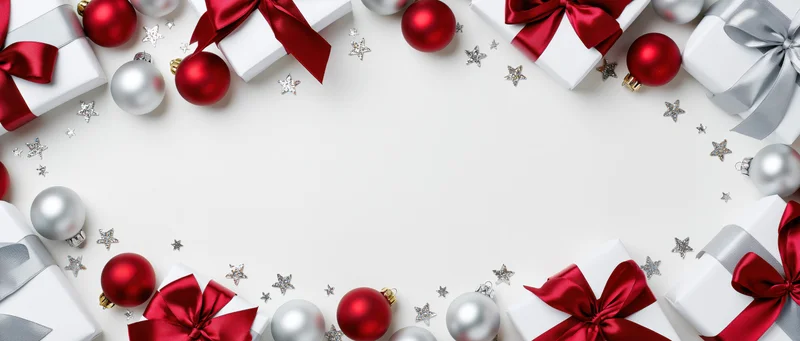 Christmas gifts and ornaments arranged in a border around a white copyspace