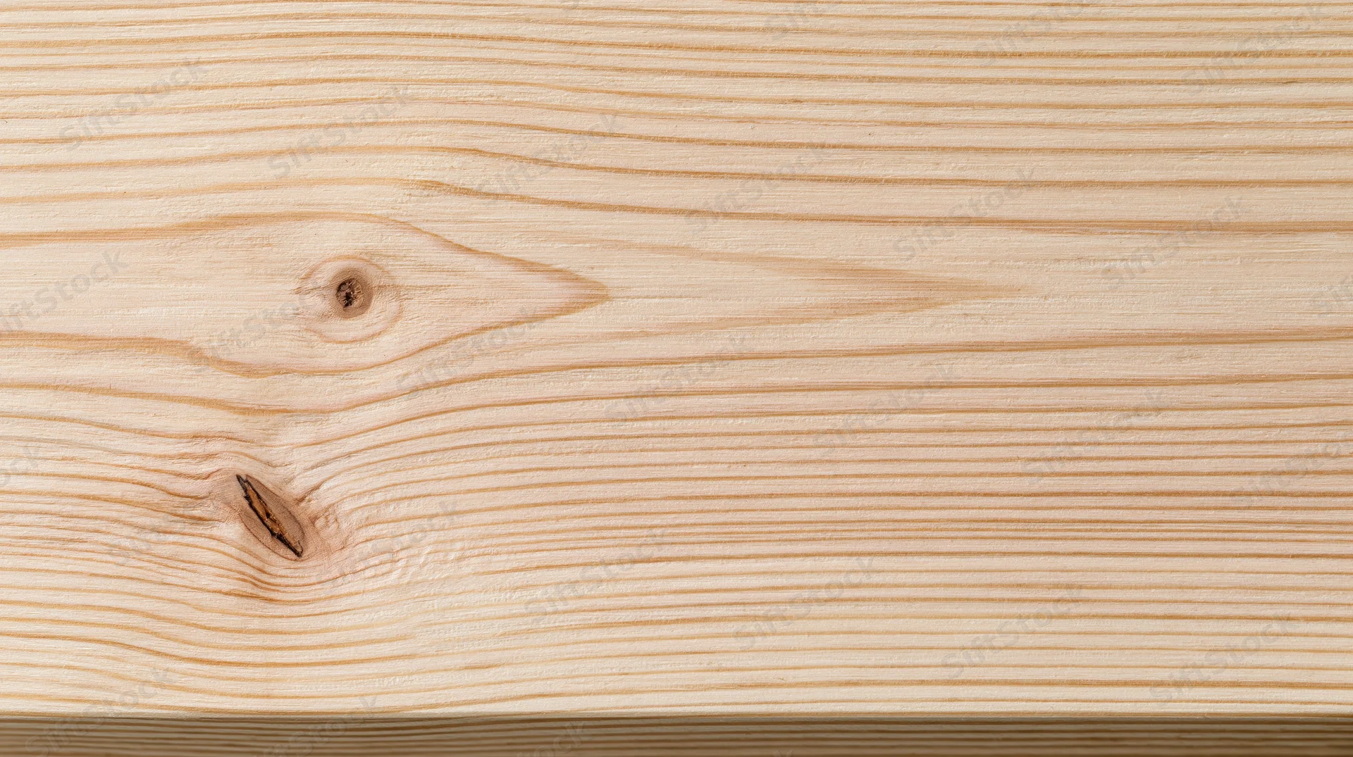 Closeup of light pine wood surface showing natural grain and knots, suitable for furniture or interior design