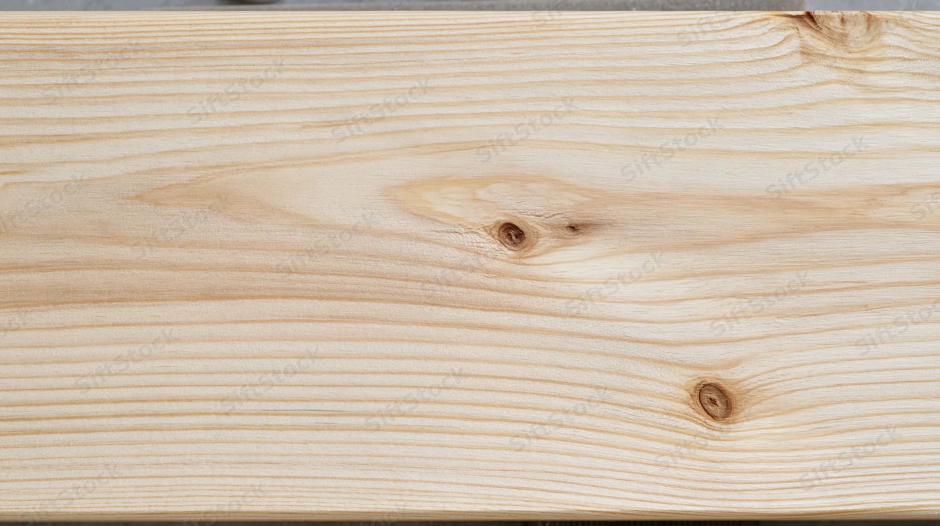 Closeup of a light pine wood plank showing natural grain and knots, horizontal surface with smooth texture