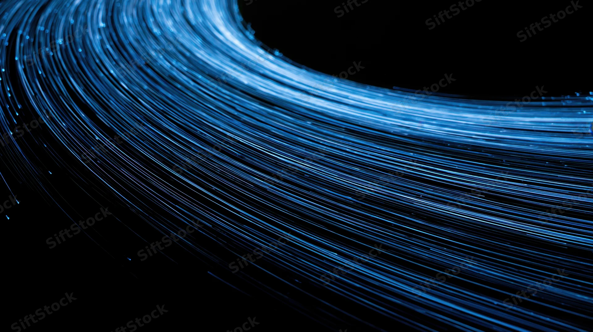 Curved bundle of blue fiber optic cables glowing in darkness