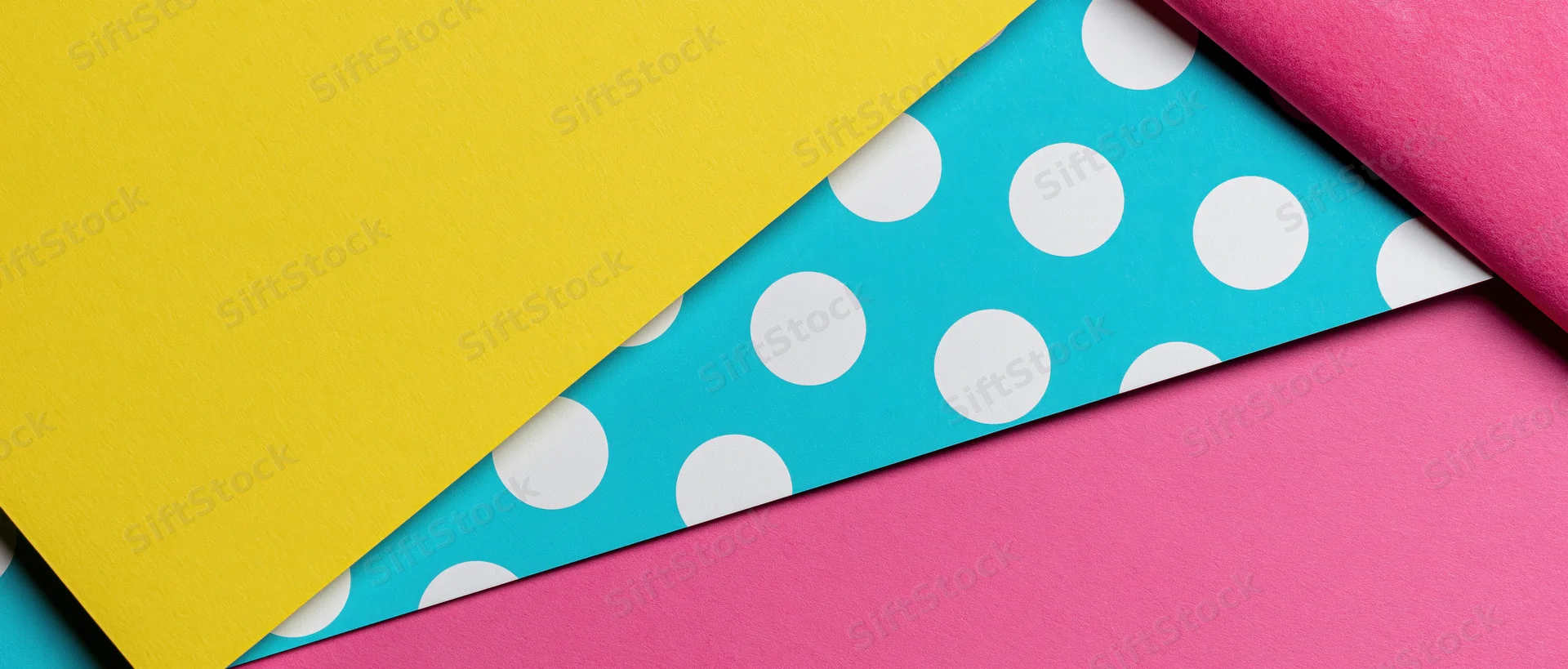 Colorful patterned paper sheets arranged in overlapping diagonal layers with polka dots and solid colors