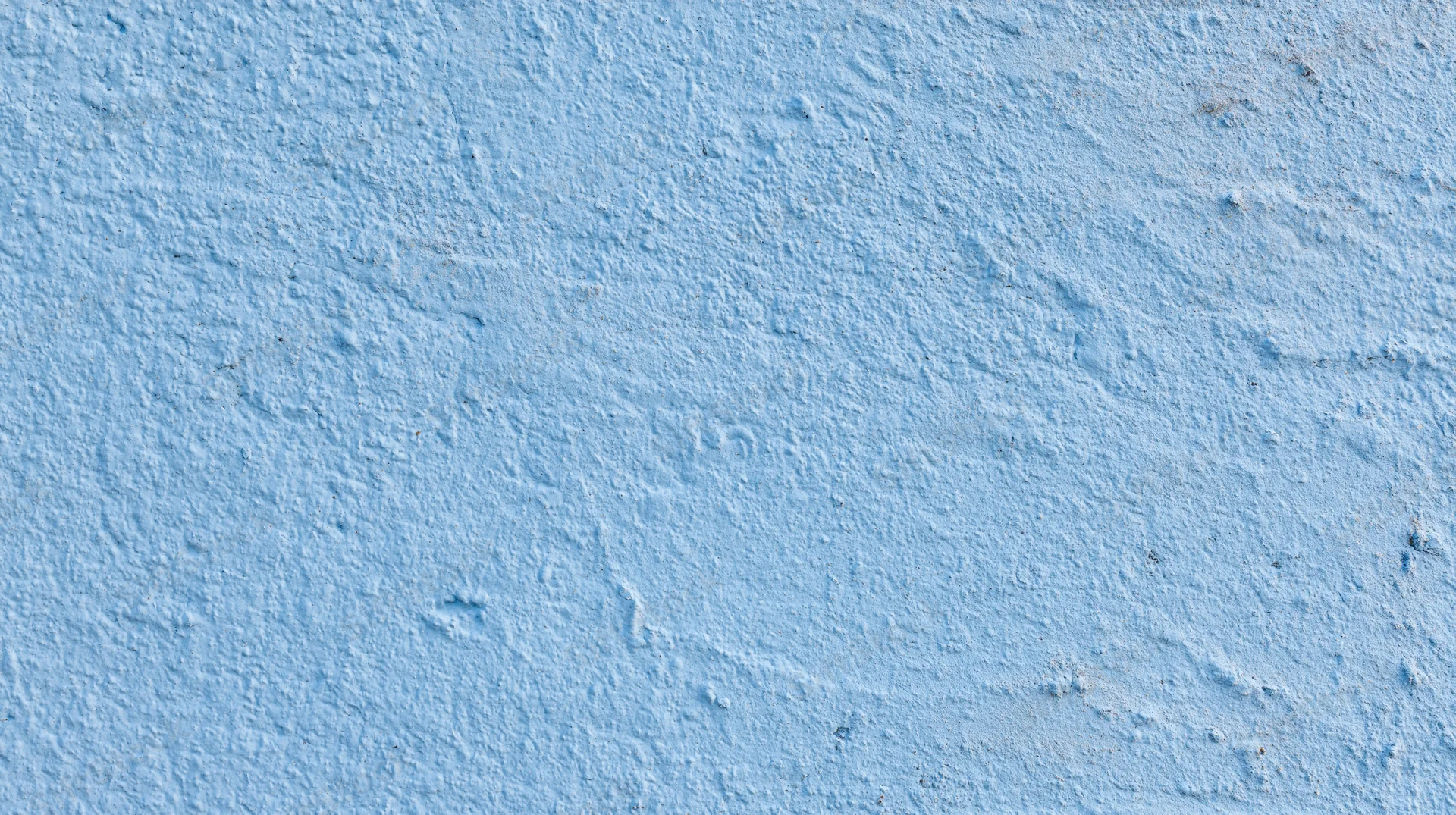 Close-up of a textured blue painted wall surface with rough plaster finish