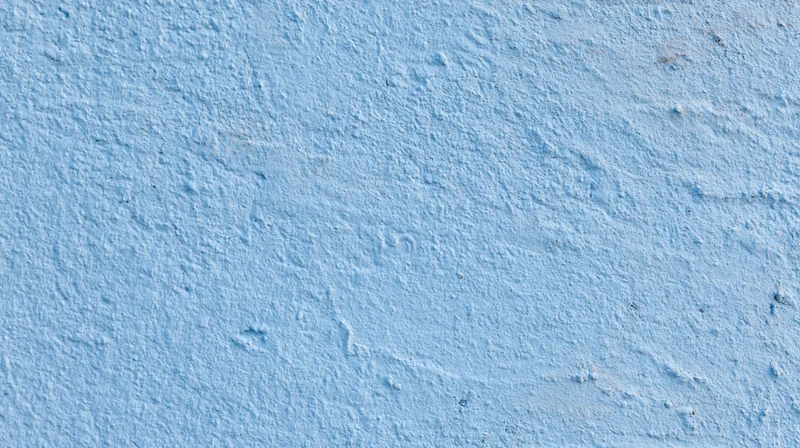 Close-up of a textured blue painted wall surface with rough plaster finish