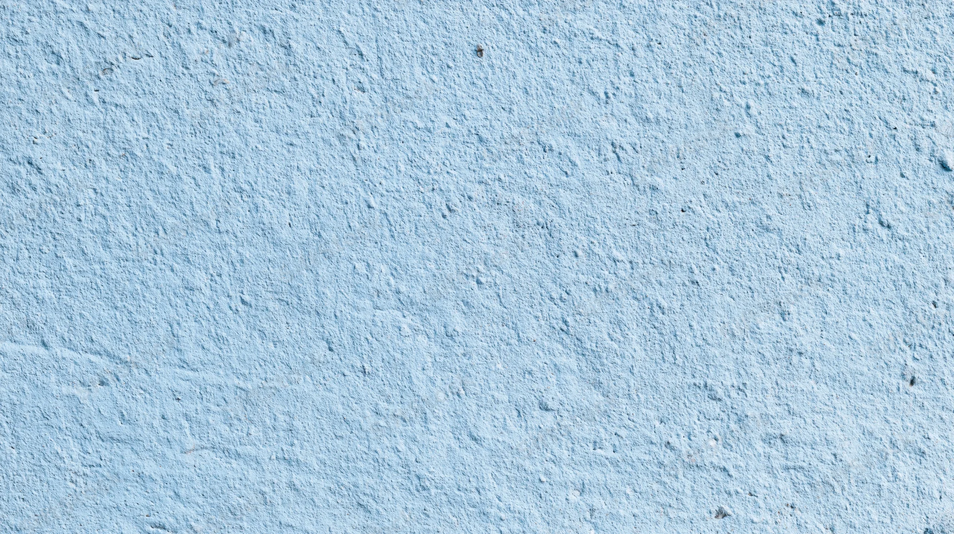 Close-up of a textured blue painted wall surface with rough plaster finish