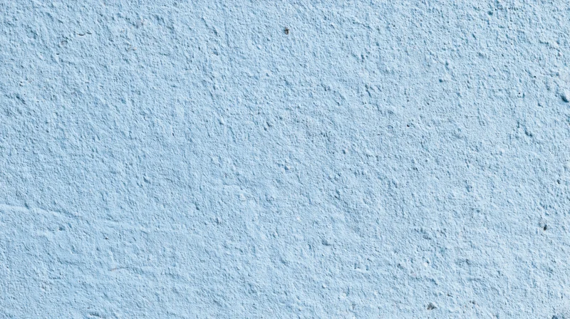 Close-up of a textured blue painted wall surface with rough plaster finish