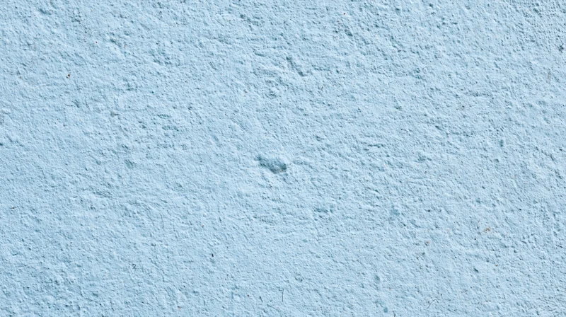 Light blue textured wall surface with rough plaster finish