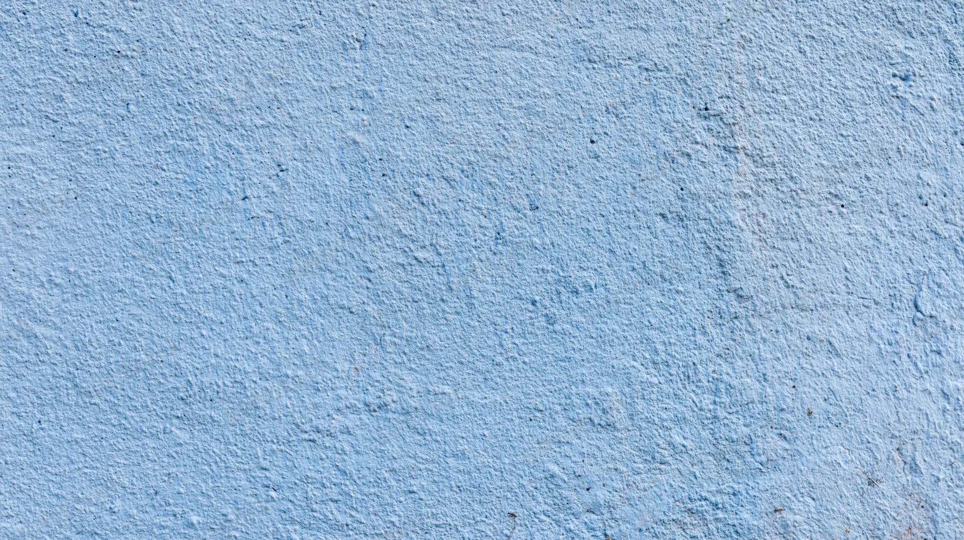 Blue painted concrete wall with rough texture and uneven surface