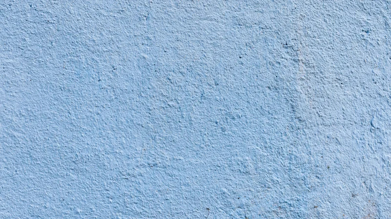 Blue painted concrete wall with rough texture and uneven surface