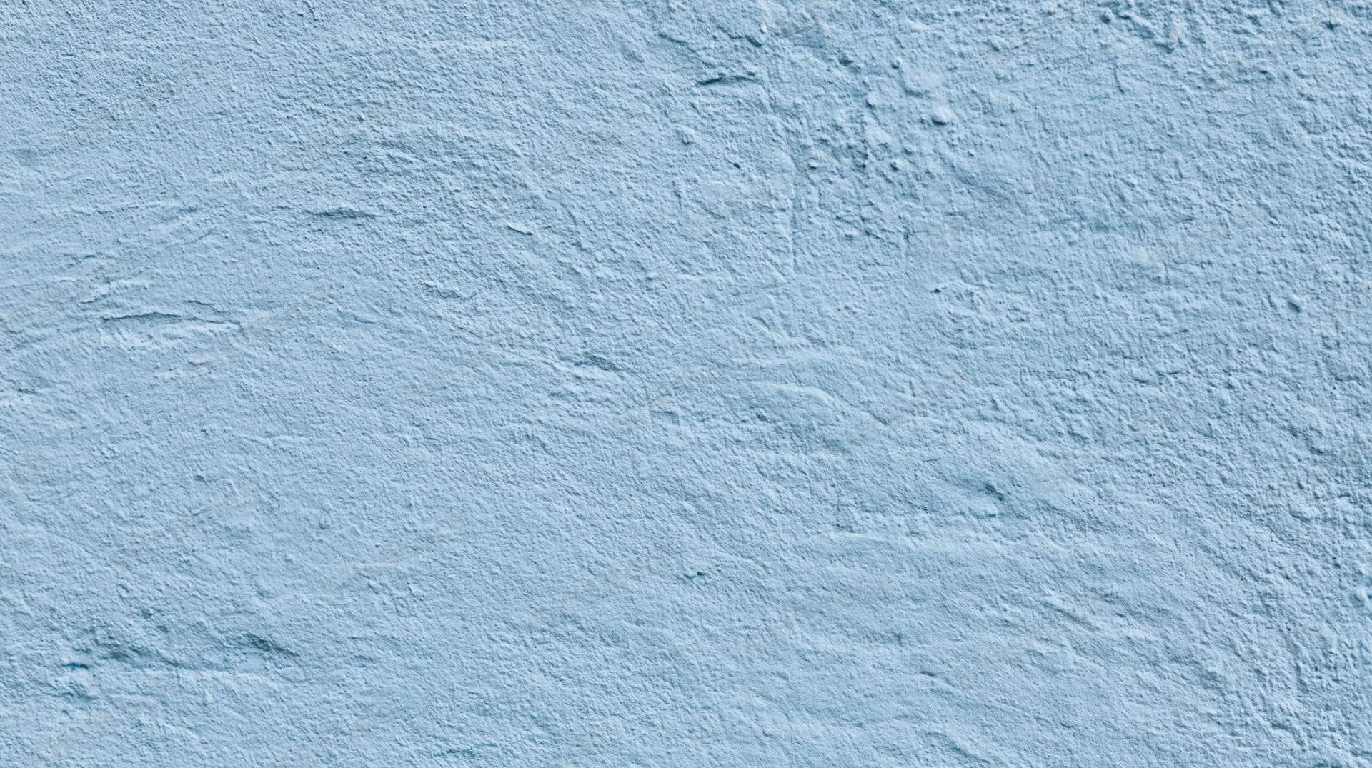 Close-up of a light blue plastered wall surface with rough texture and subtle imperfections