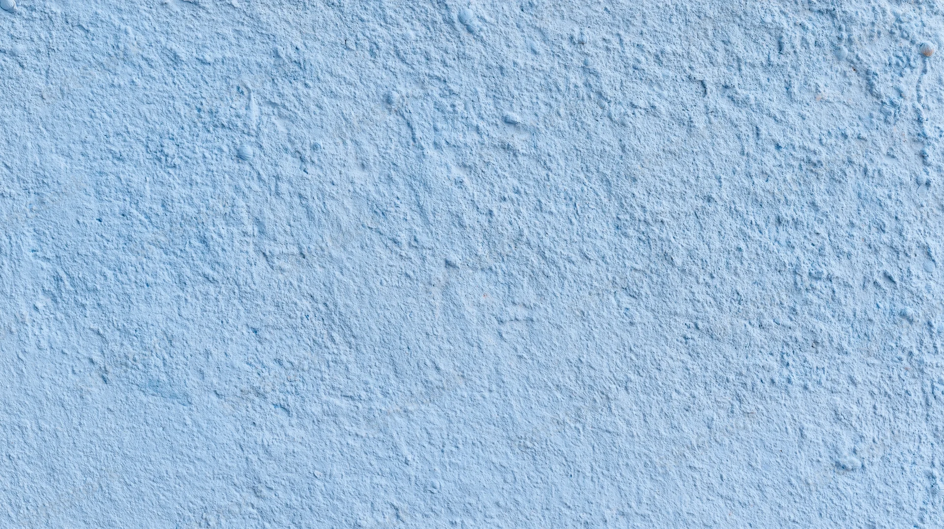Textured blue painted wall surface with rough plaster finish and even lighting