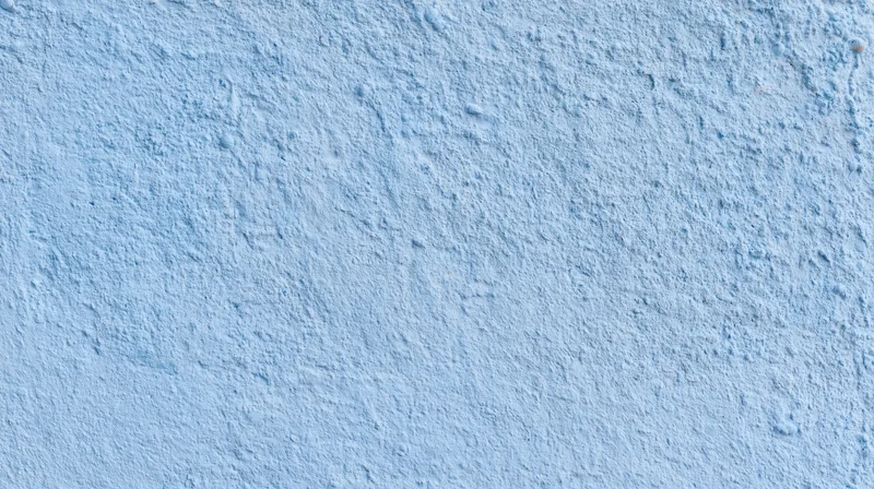 Textured blue painted wall surface with rough plaster finish and even lighting
