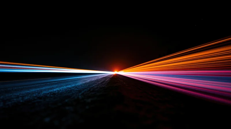 Light trails from moving vehicles on a dark road at night converging toward a distant point