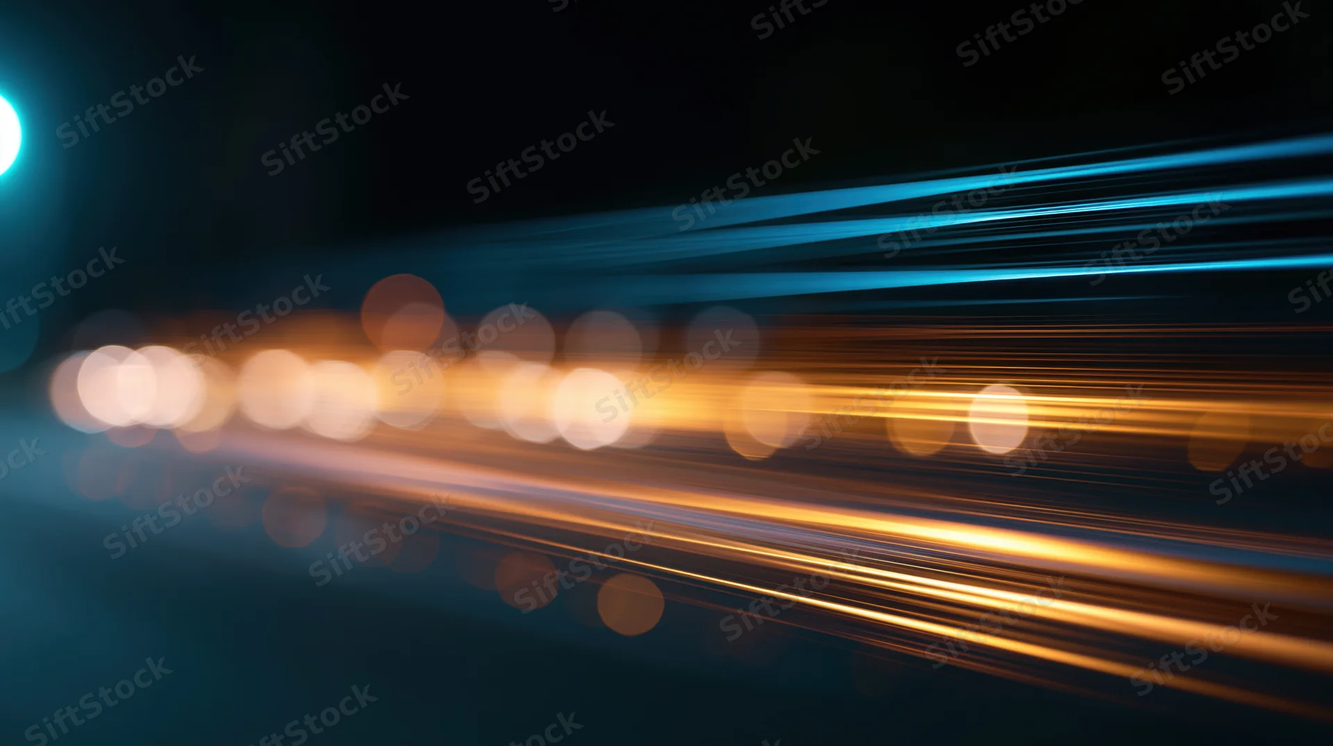 Streaks of orange and blue light moving across a dark background with bokeh highlights
