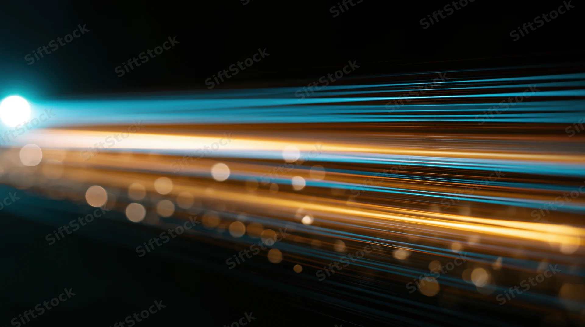 Streaks of blue and orange light moving across a dark background with bokeh highlights