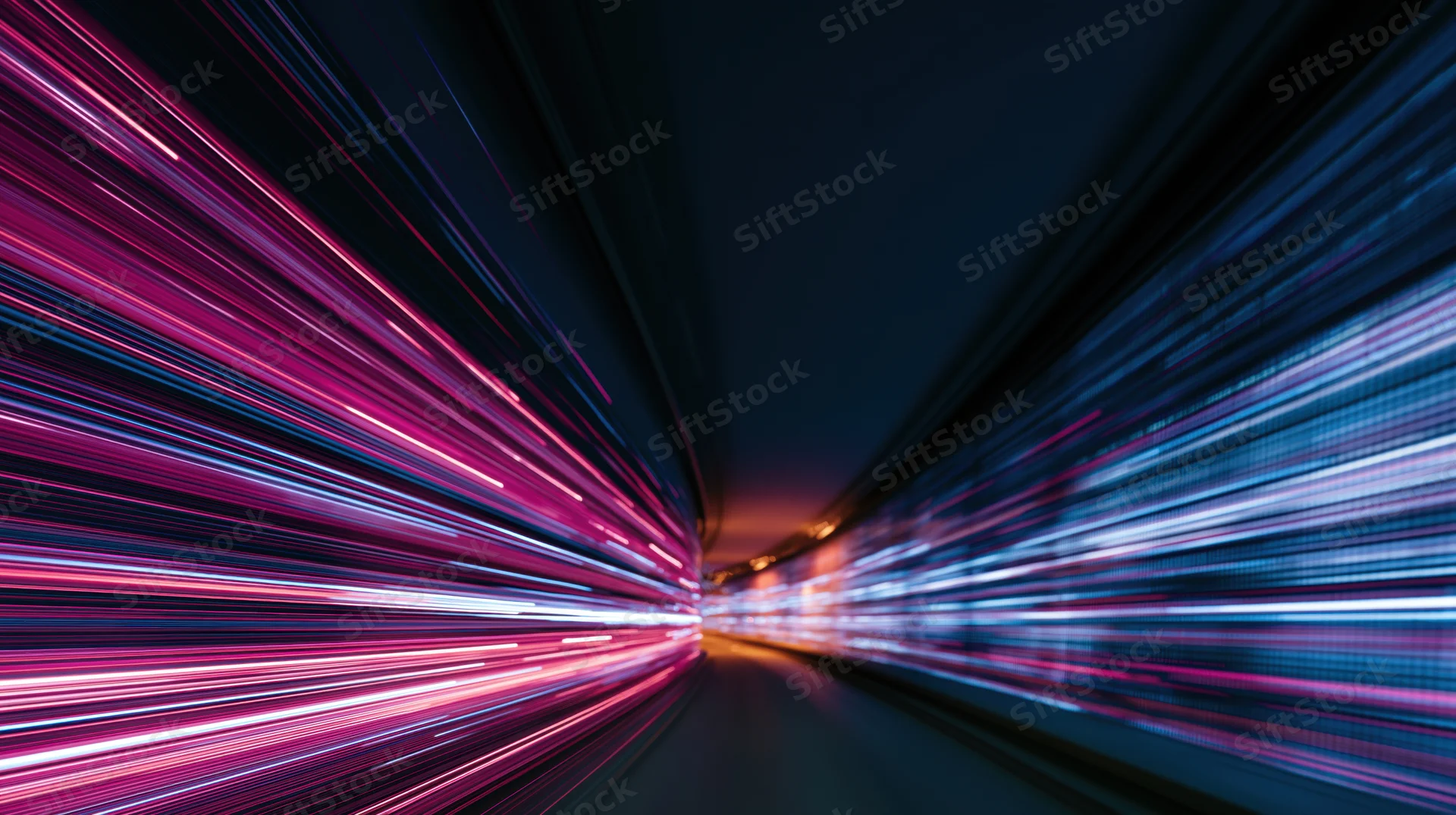 Streaks of pink and blue light moving rapidly through a dark tunnel at night