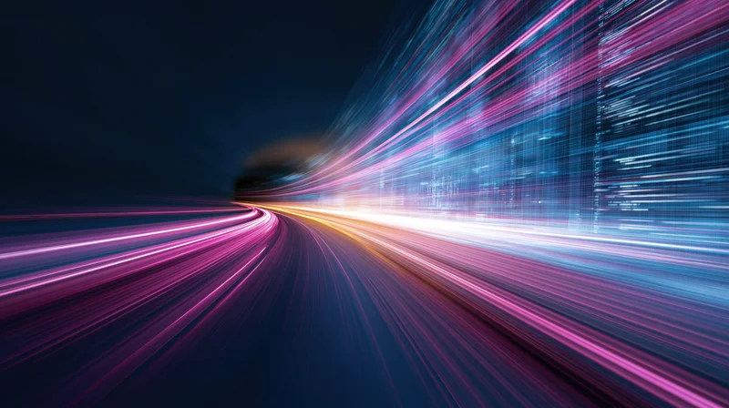 Light streaks from moving vehicles at night in a cityscape, creating abstract motion trails along a curved road