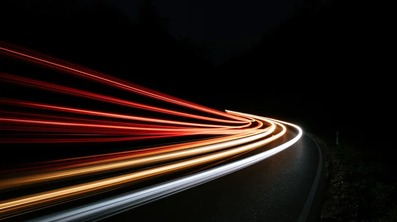 Light trails from moving vehicles on a curving road at night