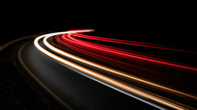 Curved road at night with light trails from moving vehicles