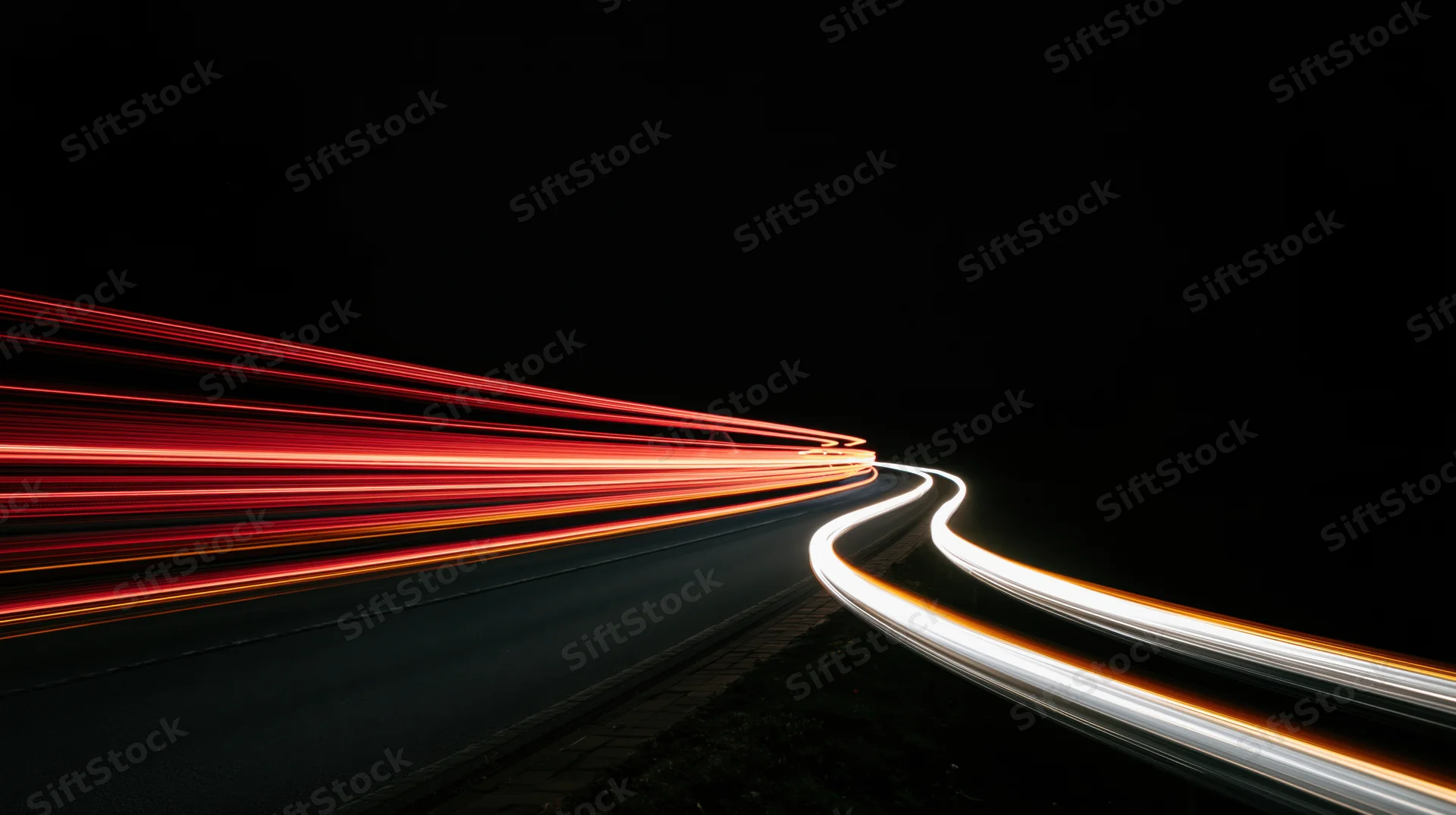 Light trails from moving vehicles on a winding road at night