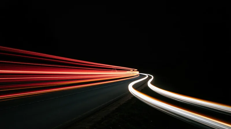 Light trails from moving vehicles on a winding road at night