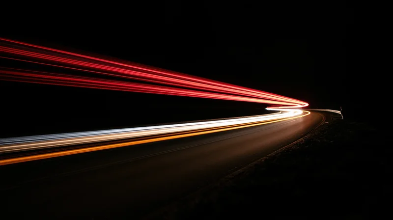 Light trails from moving vehicles on a curving road at night