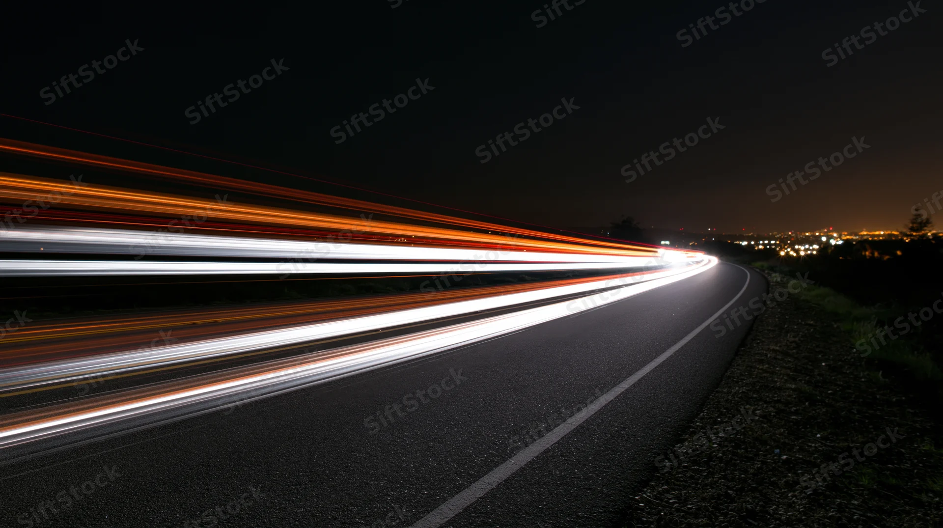 Light trails from moving vehicles on a curving highway at night