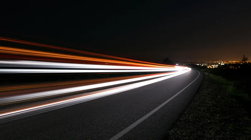 Light trails from moving vehicles on a curving highway at night