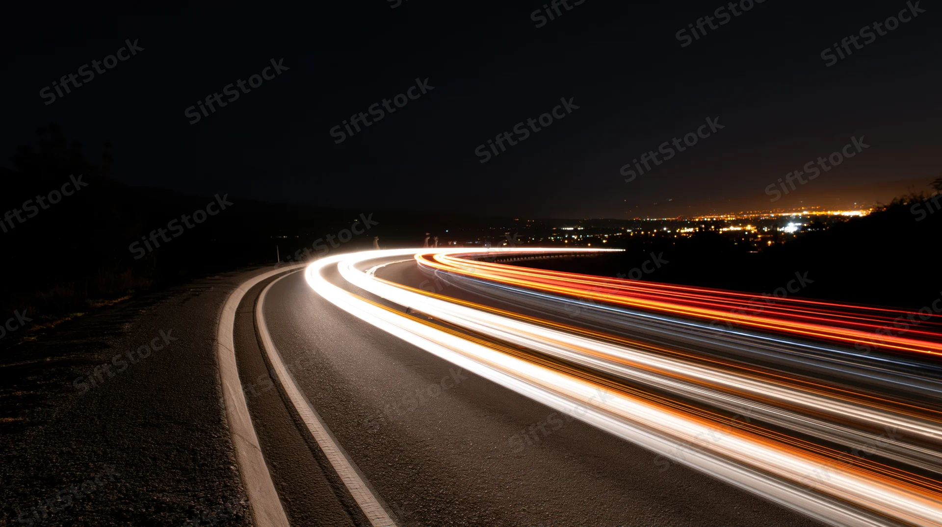 Curved highway at night with light trails from moving vehicles