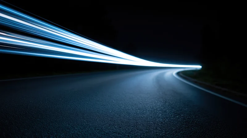 Curved asphalt road at night with light streaks from moving vehicles