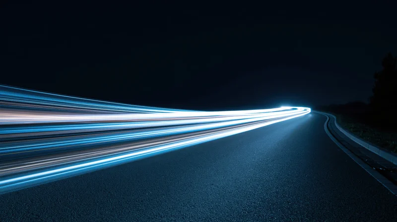 Curved asphalt road at night with light streaks from moving vehicles
