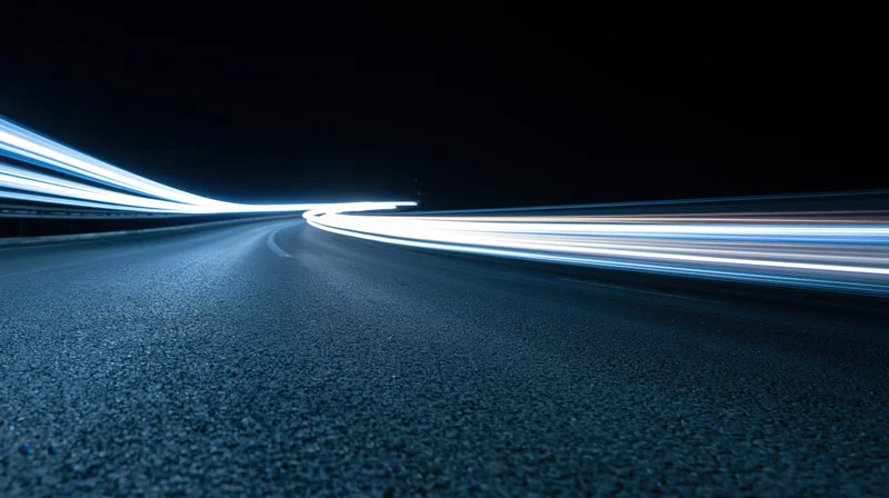 Curved asphalt highway at night with light streaks from moving vehicles