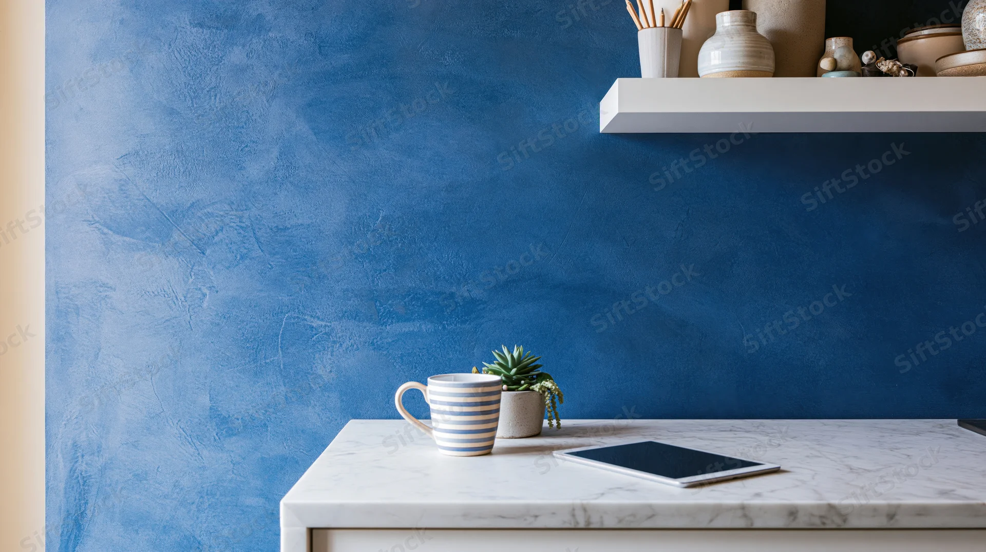 Striped ceramic mug and small succulent on marble countertop beside digital tablet in home office setting