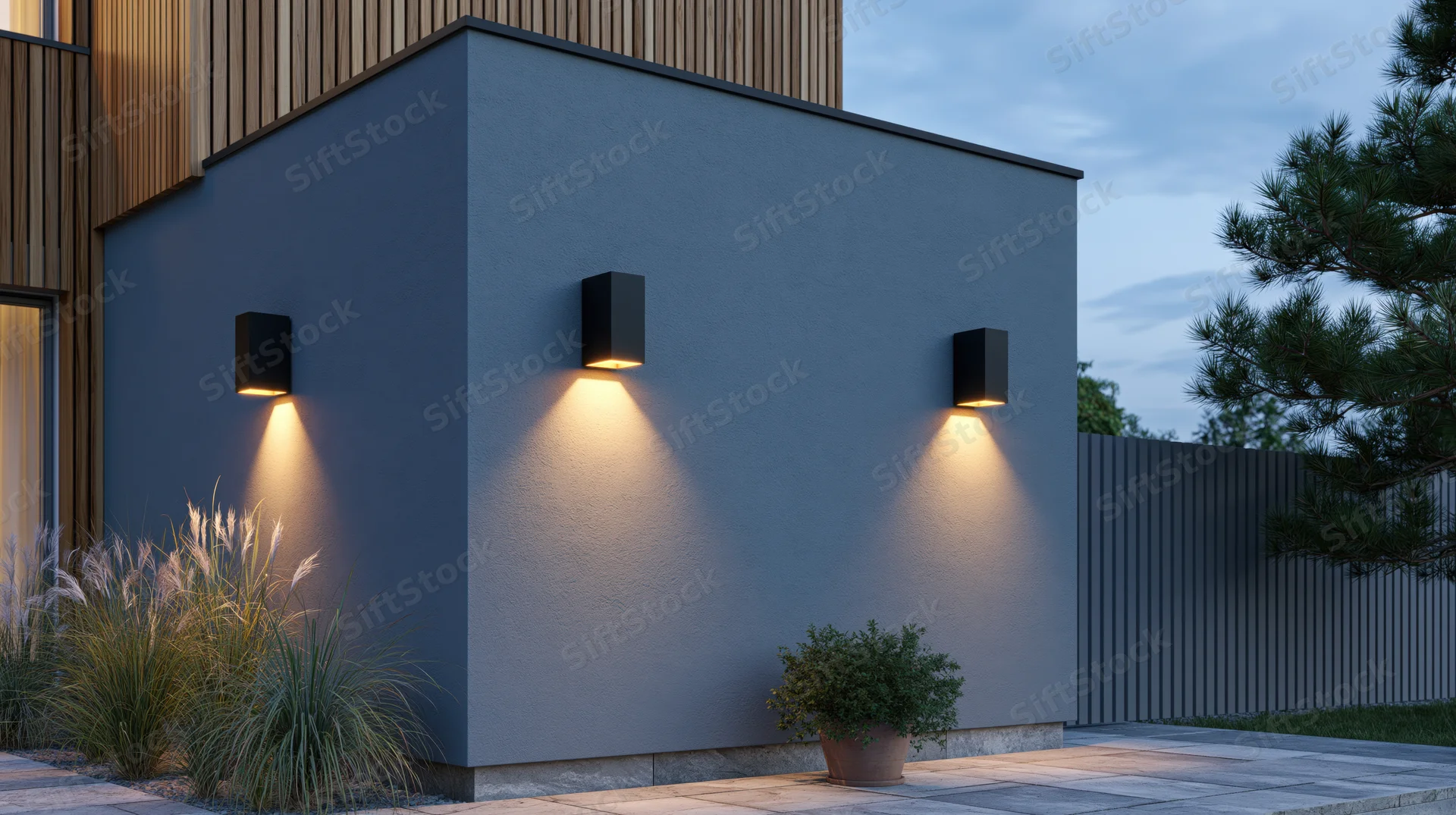 Modern house exterior with wall-mounted outdoor lights illuminating a gray facade and garden plants at dusk