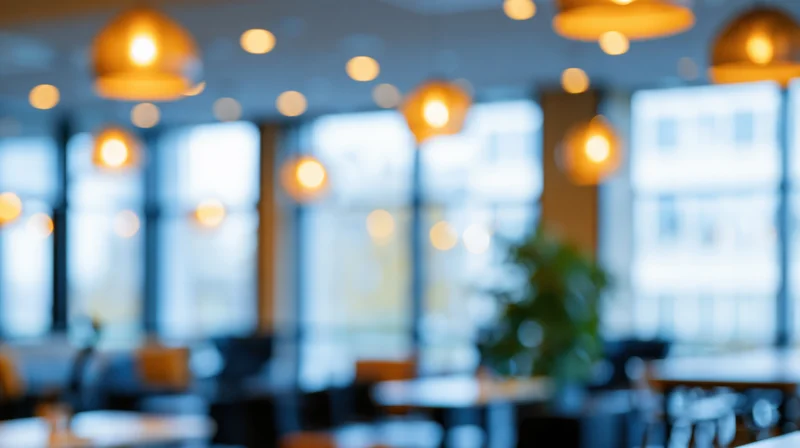Blurred interior of a modern office space with warm pendant lights and large windows
