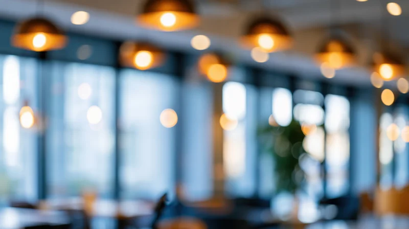 Blurred interior of a modern office space with warm pendant lights and large windows