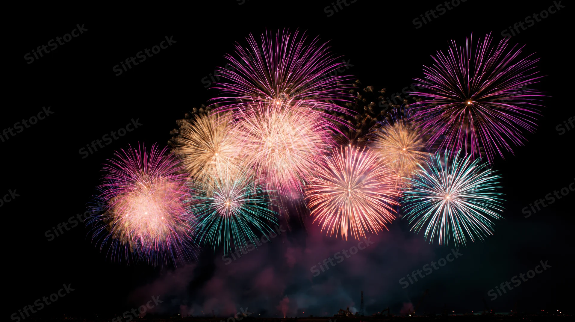 Colorful fireworks exploding in the night sky over a cityscape during a celebration event