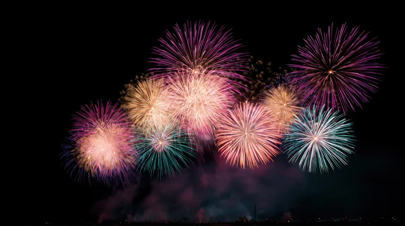 Colorful fireworks exploding in the night sky over a cityscape during a celebration event