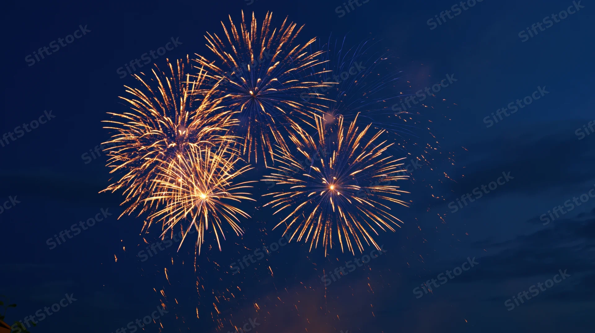 Golden fireworks bursting in the dark night sky during a celebration