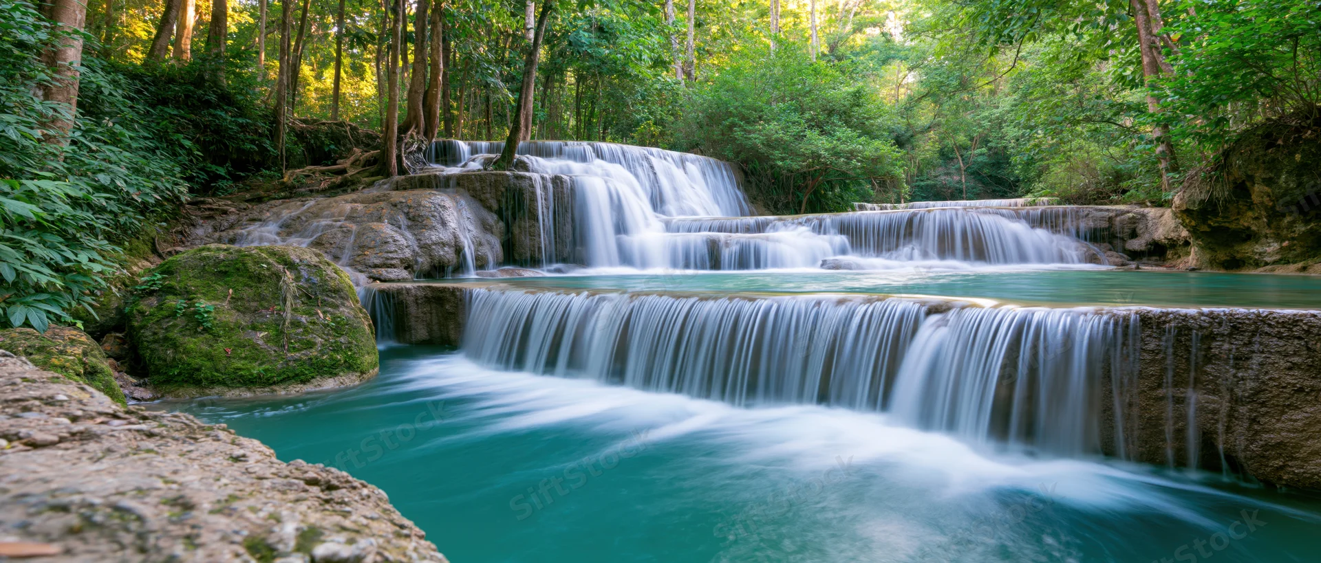 Cascading waterfall flowing over mossy rocks in a lush tropical forest