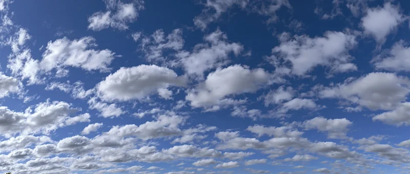 Scattered white cumulus clouds across a bright blue sky in daytime outdoor view