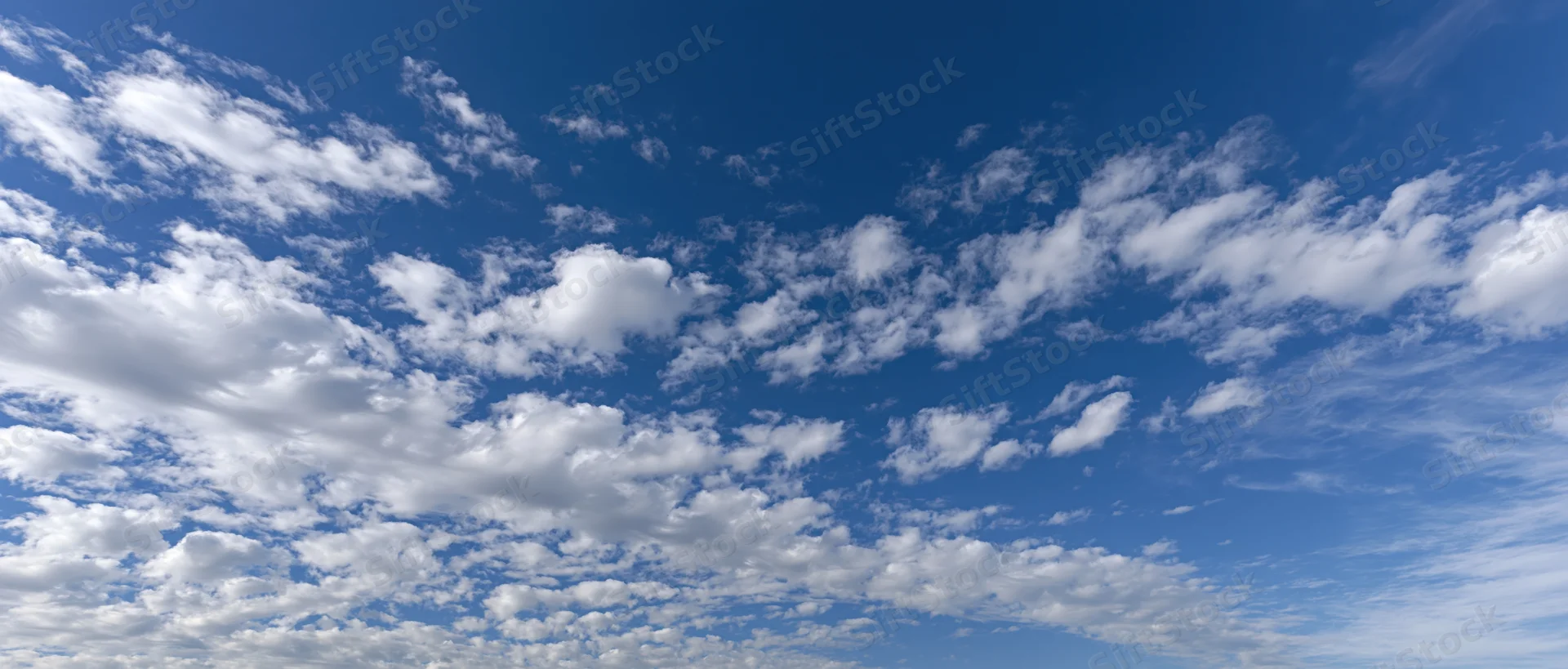 Scattered white cumulus clouds floating across a clear blue sky during daytime