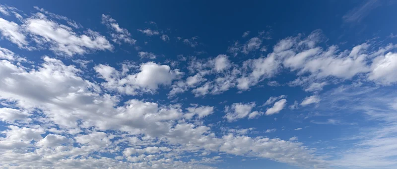 Scattered white cumulus clouds floating across a clear blue sky during daytime