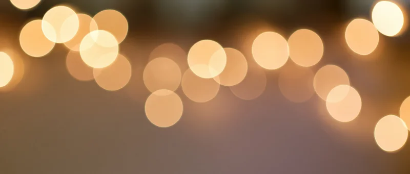 Warm glowing bokeh lights arranged in a string across a blurred background with copyspace below