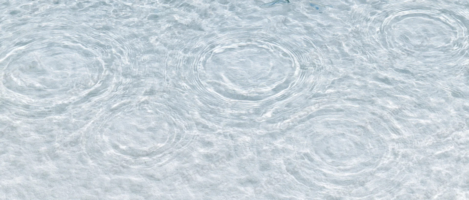 Water surface with circular ripples from droplets creating a textured pattern