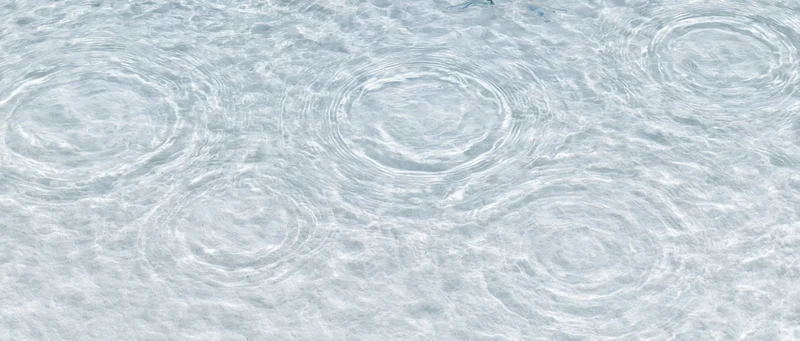 Water surface with circular ripples from droplets creating a textured pattern